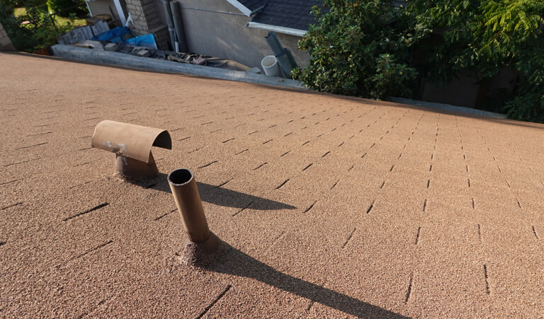 A brown roof with a pipe laying on it.