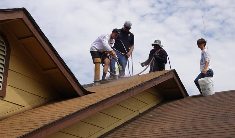 Three men are working on a roof.