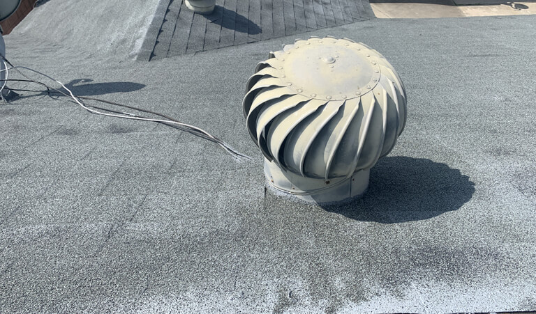 A white vent on the side of a roof with a big size fan