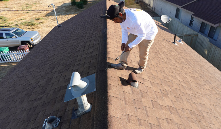 A man standing on top of the roof fixing his boots.