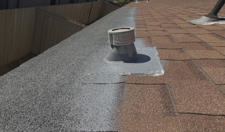 A roof with a vent on it and the roof is covered in asphalt.