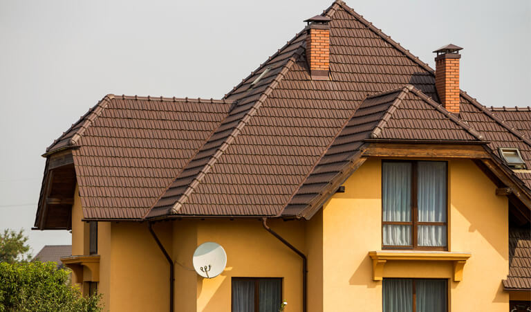 A brown roof with a satellite dish on the side of it.