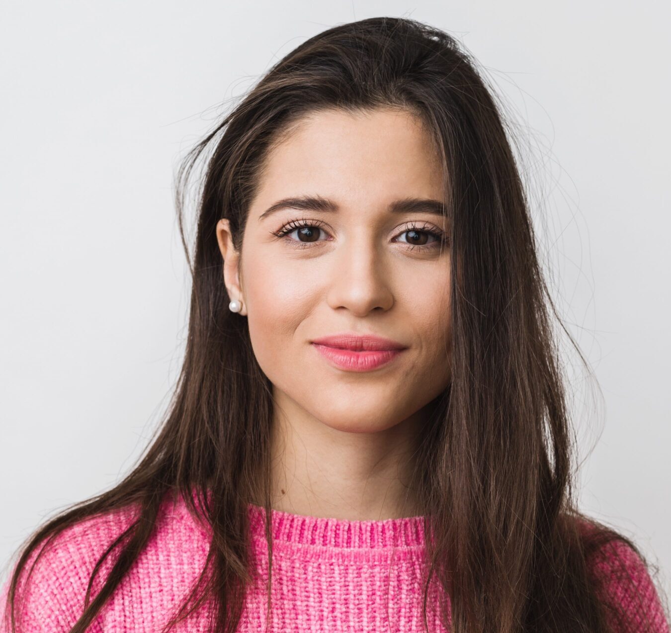 A woman in pink sweater standing next to wall.